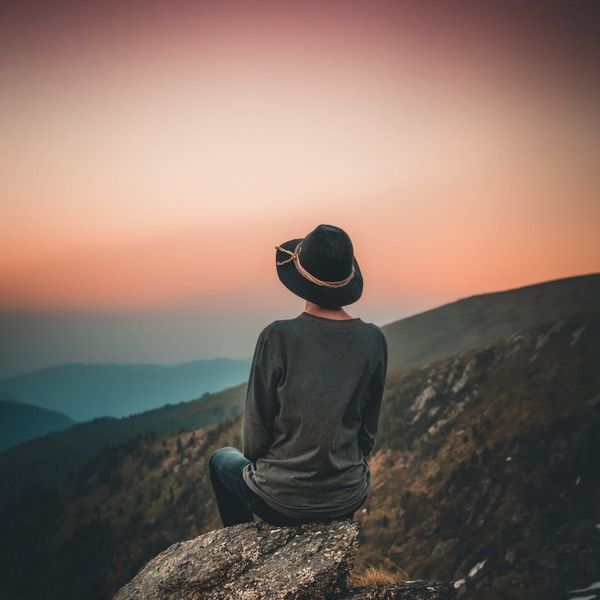 A person meditating in a calm natural environment with a sunset color filter.